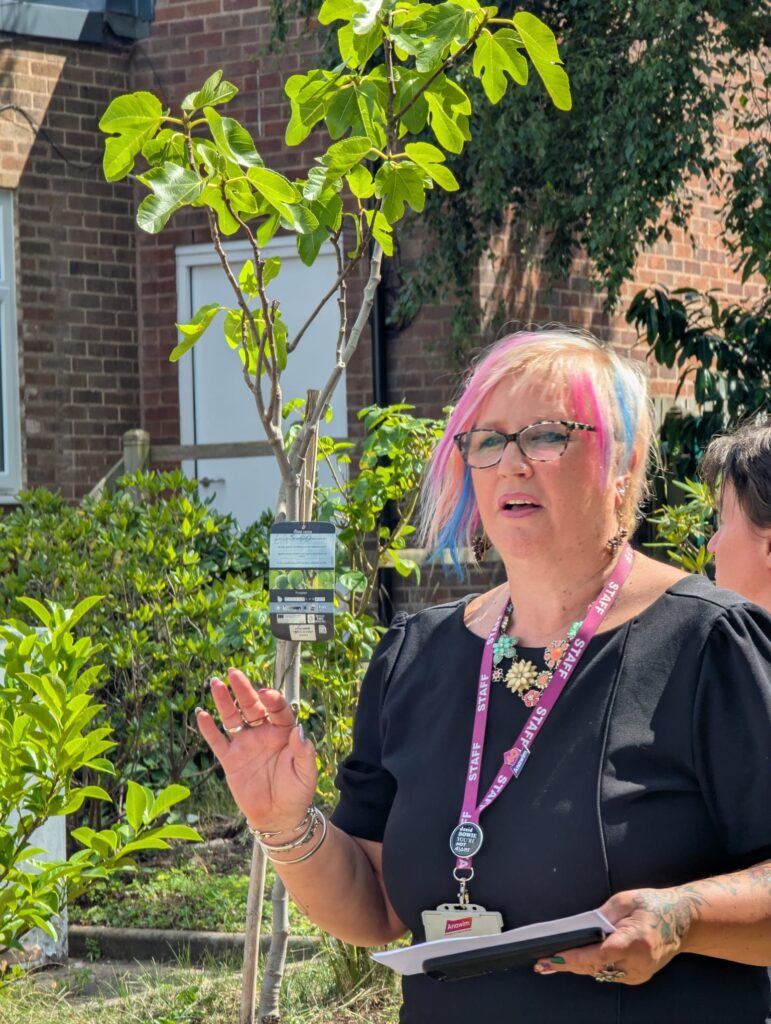 Joy ceremonially planting the fig tree with Fruit and Nut Village.
